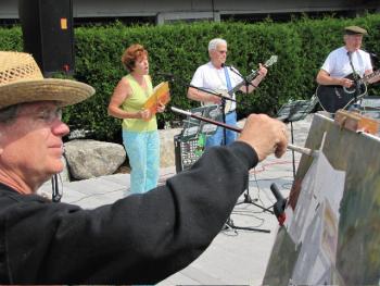 John Seitzer while painting at last year’s Art@Waterfront Park while the Greenfields perform onstage. Seitzer, the Greenfields and dozens of artists perform or exhibit on Saturday, Sept. 1 at Whale/Waterfront Park on Commercial Street in Boothbay Harbor.